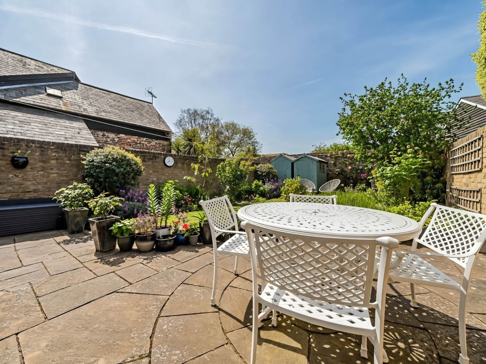 A garden with a table and chairs surrounded by flower pots at CobNut Cottage in Sandwich