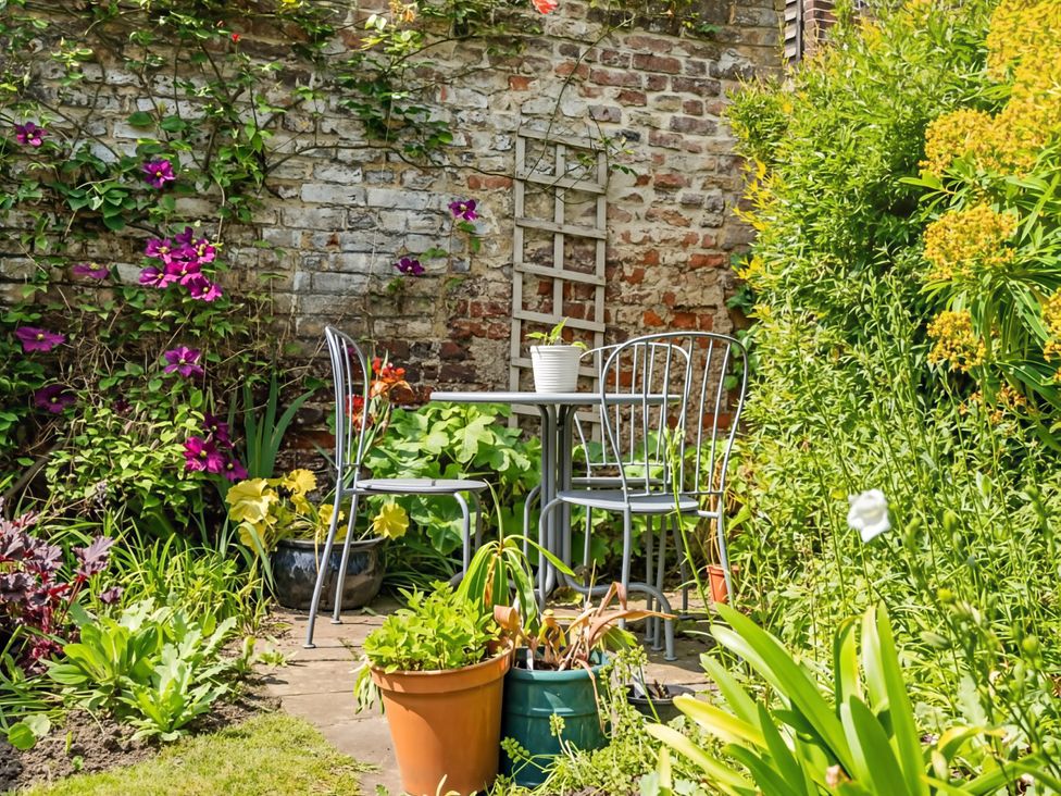A table and two chairs surrounded by plants in the garden at CobNut Cottage Sandwich
