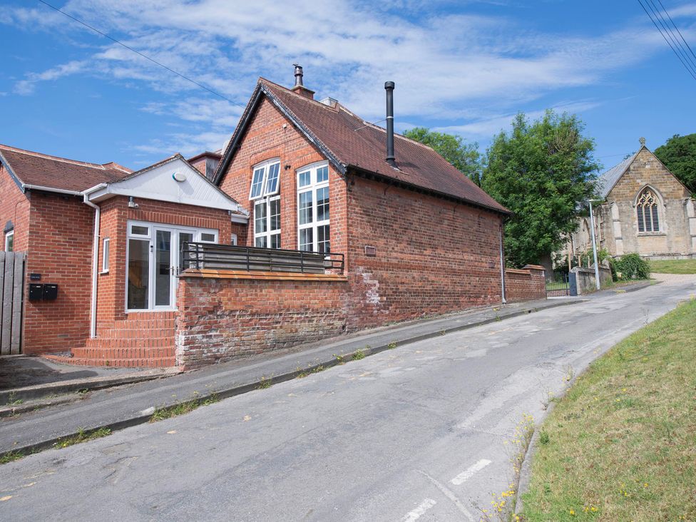 A house with a balcony and chimney on a street next to a church at The Old School House 