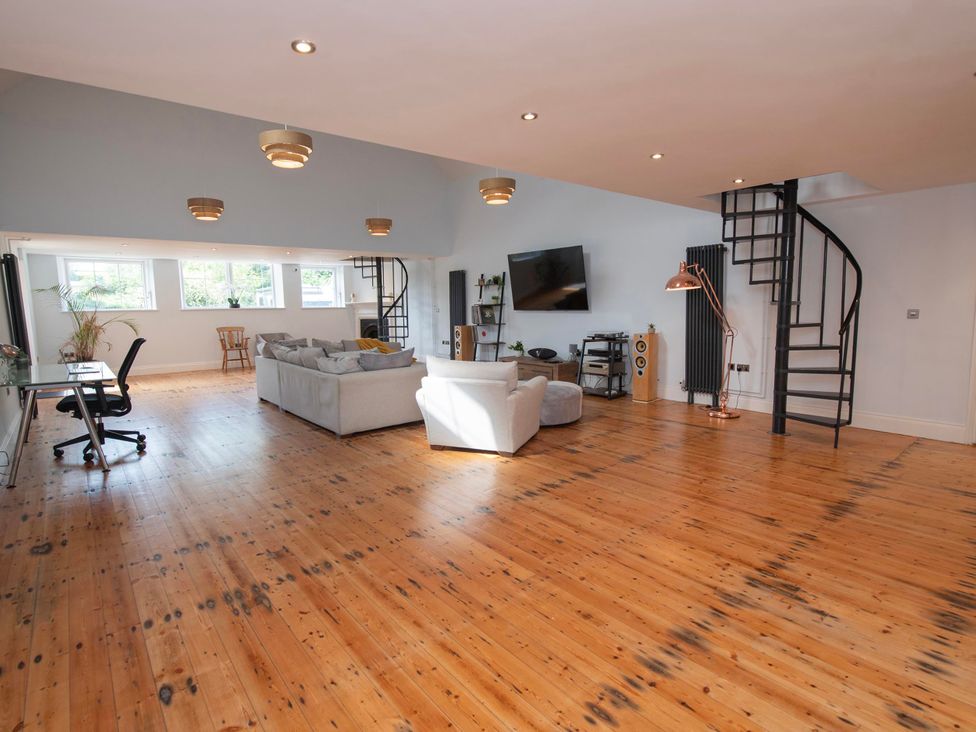 A living room with a sofa, desk, and spiral staircase at The Old School House 