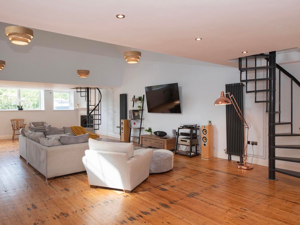 A living room with a sofa, tv, and staircase at The Old School House 