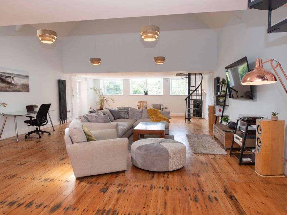 A living room with a sofa, coffee table, desk, and television at The Old School House 