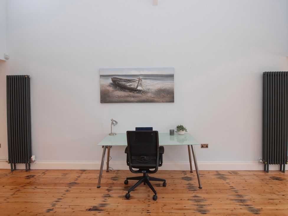 An office with a desk, chair, and painting at The Old School House