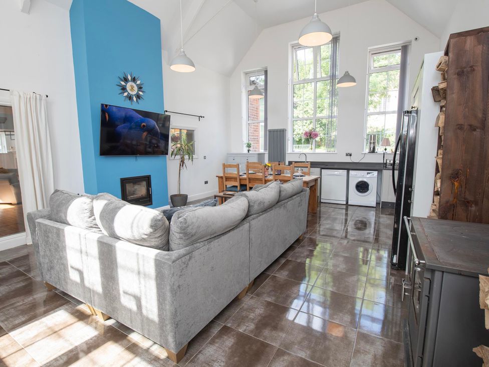 A living room with a sofa, television, and dining area at The Old School House 