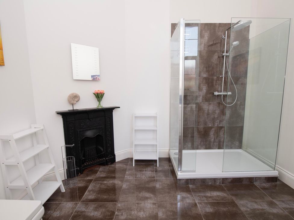 A bathroom featuring a shower, mirror, and shelf at The Old School House