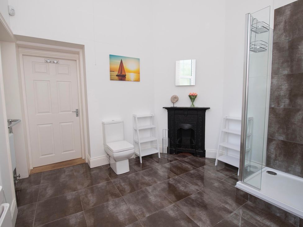 A bathroom with a toilet, shower, shelves and a picture at The Old School House