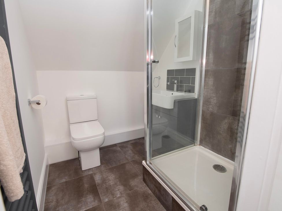 A bathroom with a toilet, shower, and sink at The Old School House