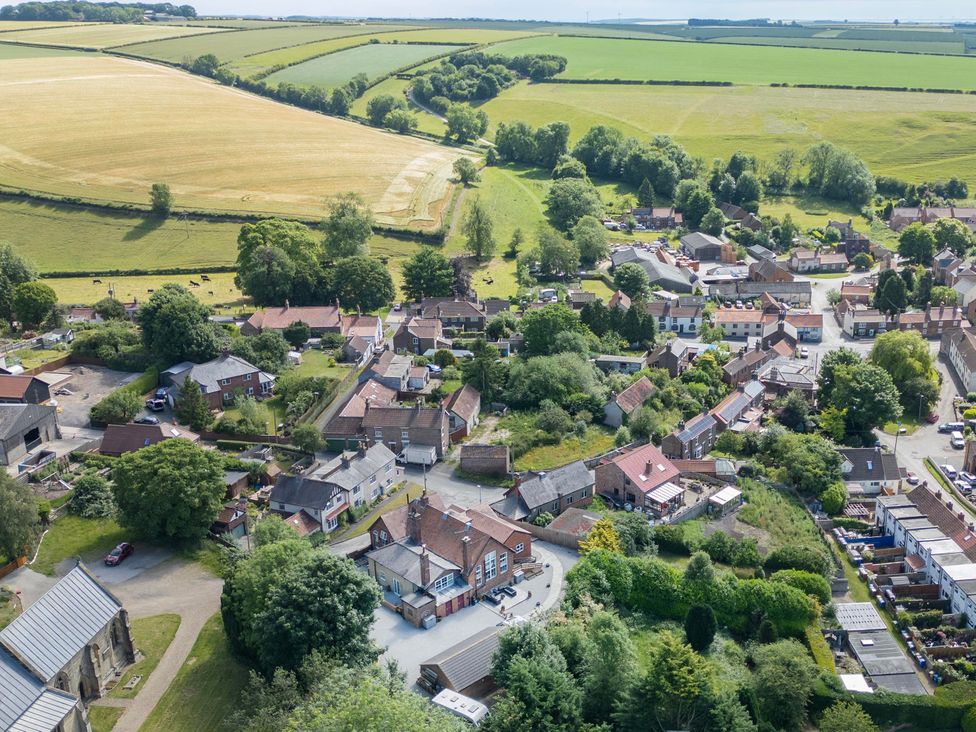 An aerial view of a village with houses and fields at The Old School House 
