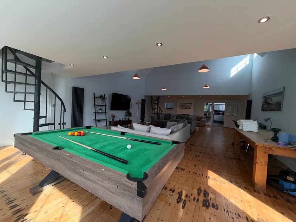 A living room with a pool table and staircase at The Old School House in Langtoft