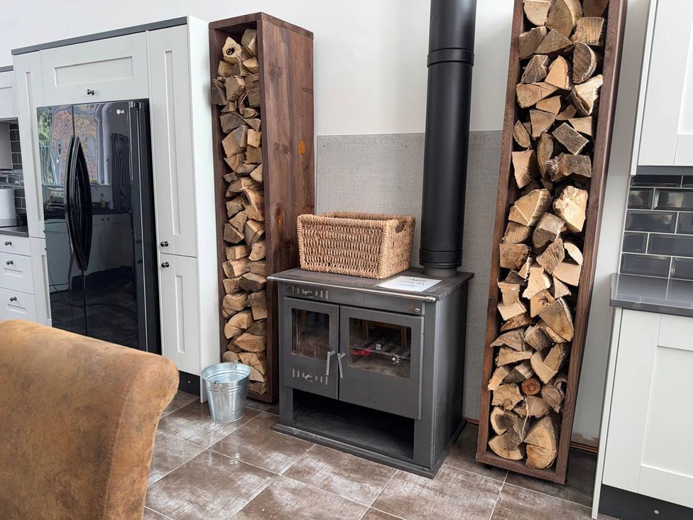A kitchen with a wood stove and firewood storage at The Old School House in Langtoft