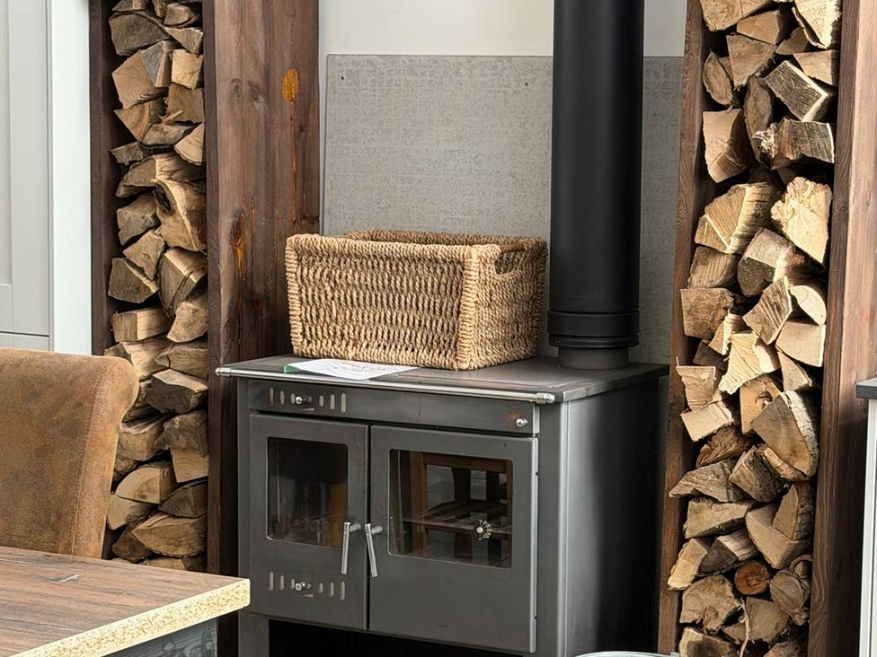A living room with a stove and stacked wood at The Old School House in Langtoft
