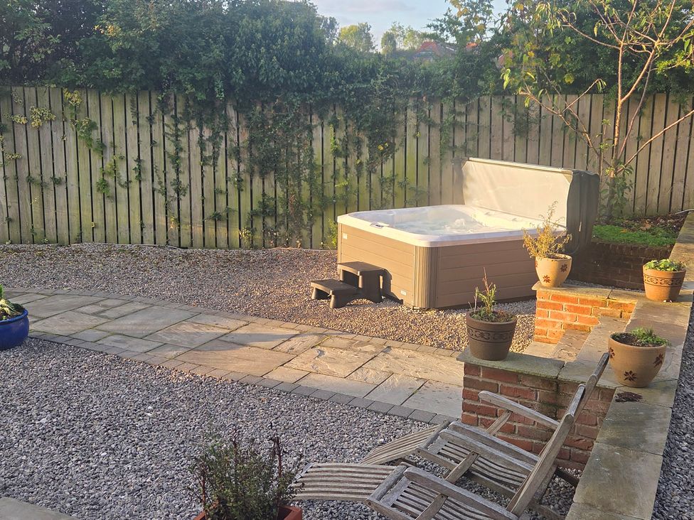 A garden with a hot tub and potted plants at The Old School House in Langtoft
