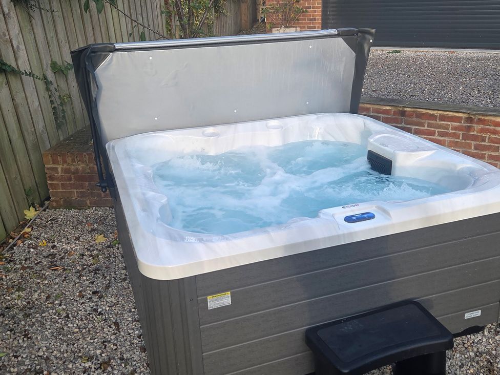 A hot tub with water and cover in an outdoor area at The Old School House in Langtoft