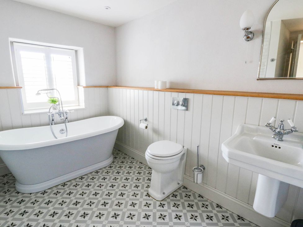 A bathroom with a bathtub, toilet and sink at Rheidiol St Davids