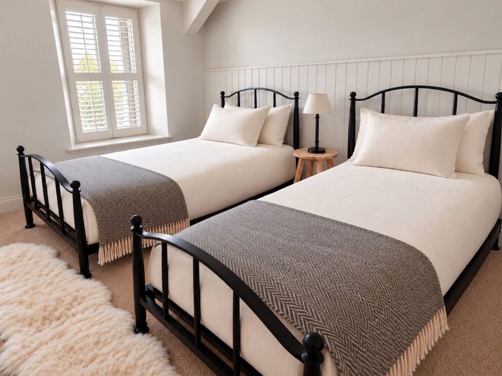 A bedroom with two beds and a side table at Rheidiol in St Davids
