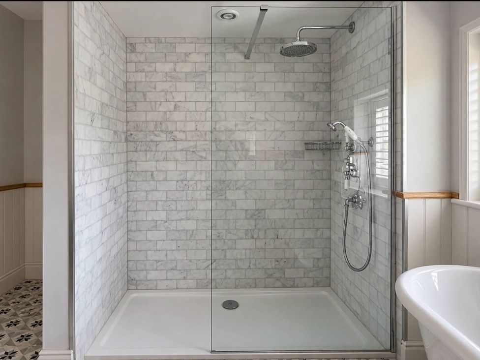 A shower with glass door and marble walls at Rheidiol in St Davids