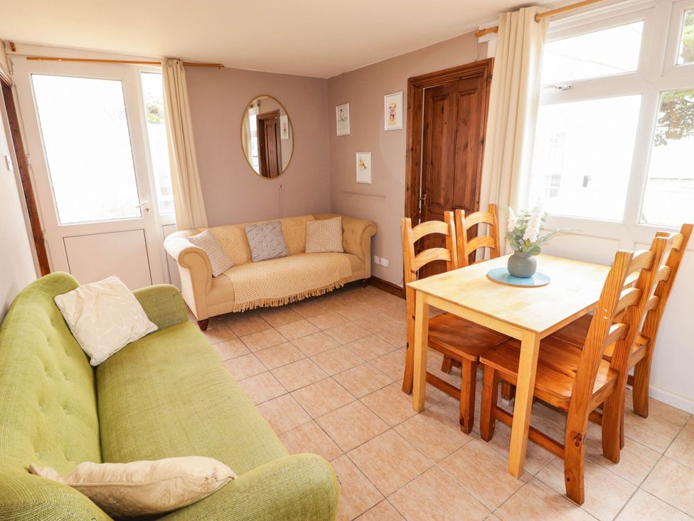 A living room with a green sofa and a dining table at Chalet 242 Carmarthen Bay in Kidwelly