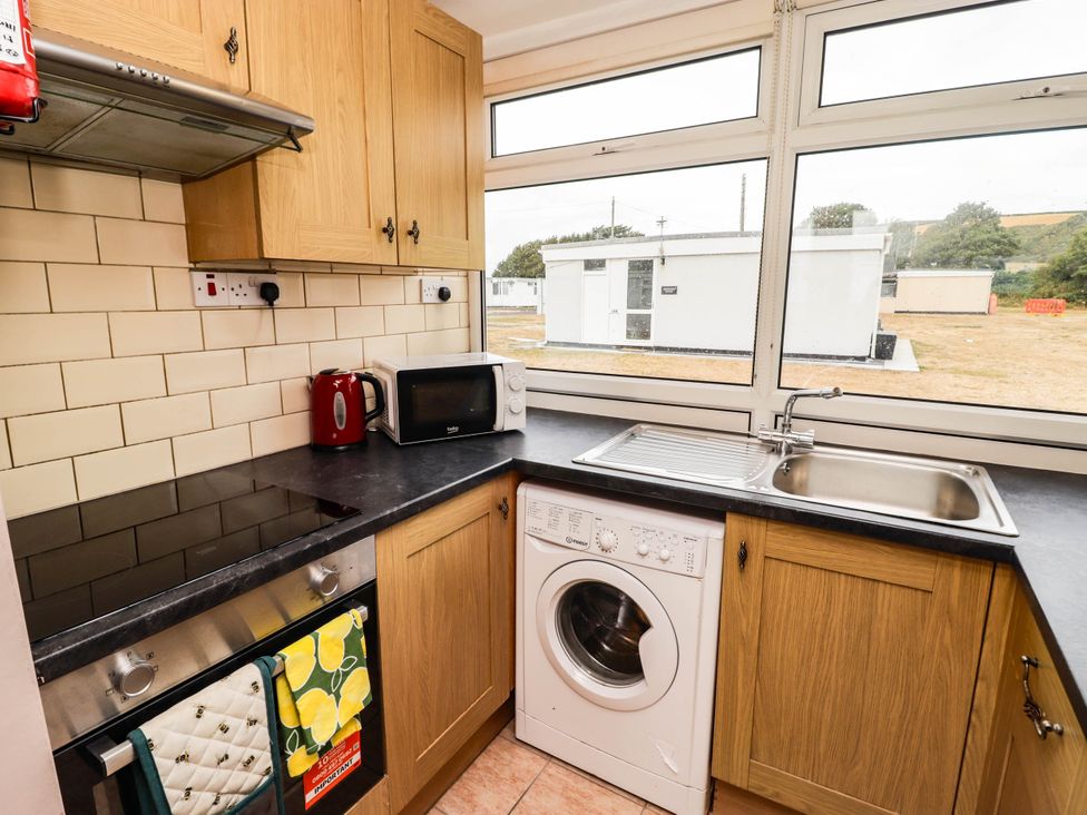 A kitchen with cabinets, sink, and washing machine at Chalet 242 Carmarthen Bay in Kidwelly