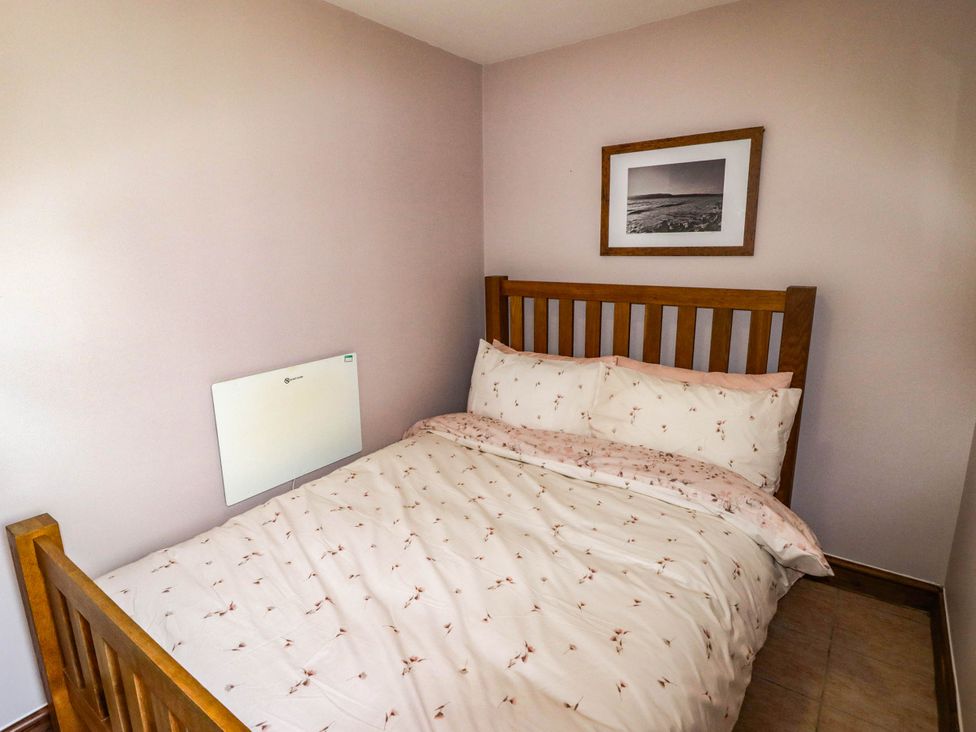 A bedroom with a bed and wall heater at Chalet 242 Carmarthen Bay in Kidwelly