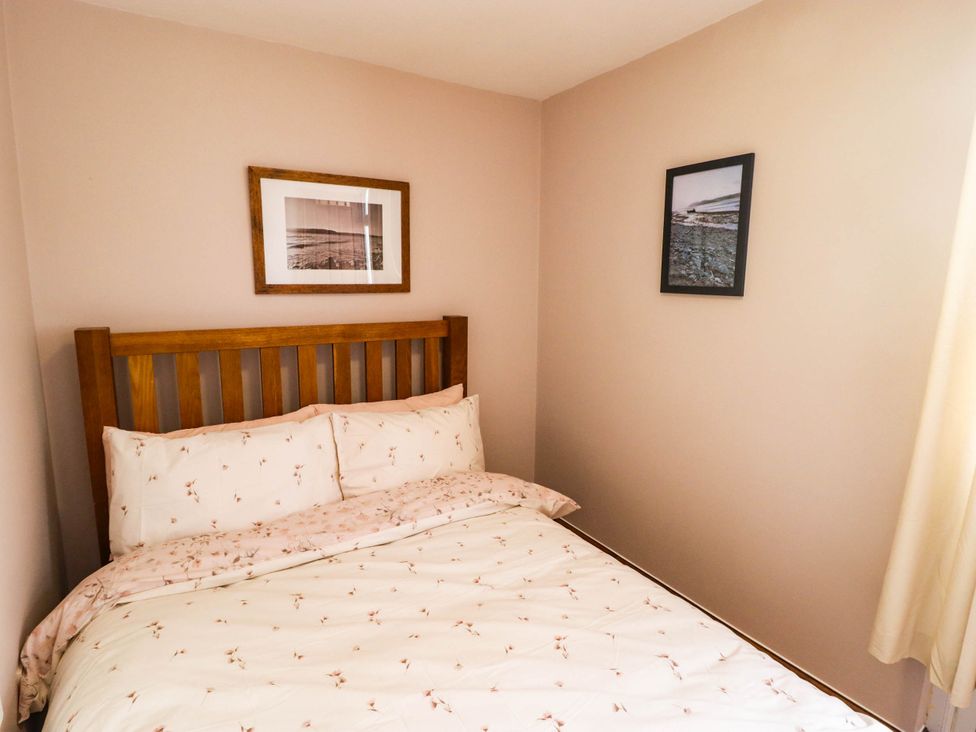 A bedroom with a bed and framed pictures at Chalet 242 Carmarthen Bay in Kidwelly