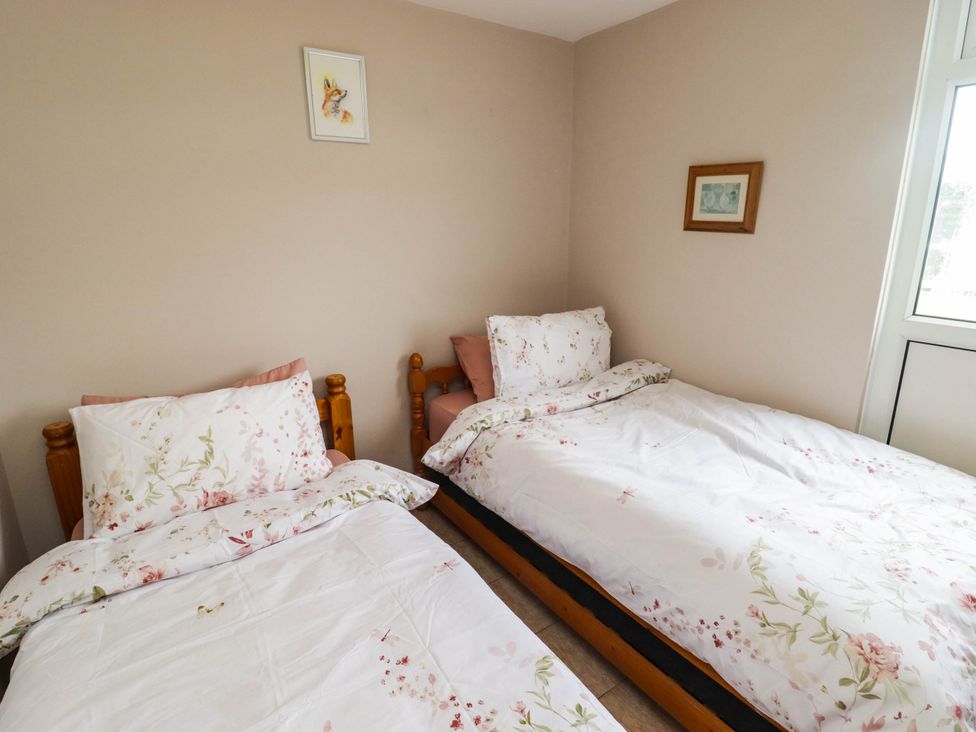 A bedroom with two beds and artwork on the wall at Chalet 242 Carmarthen Bay in Kidwelly
