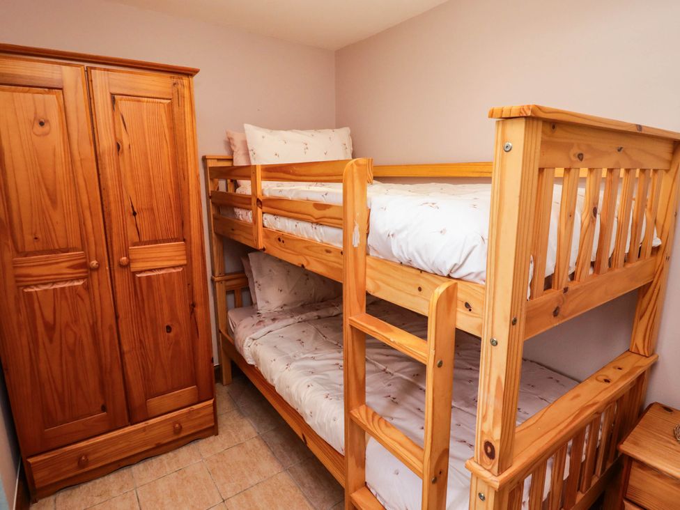 A bedroom with a bunk bed and a wardrobe at Chalet 242 Carmarthen Bay in Kidwelly