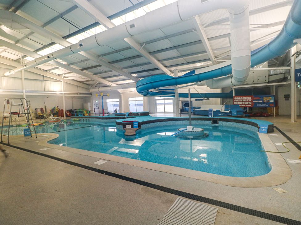 An indoor pool with a water slide and a lifeguard chair at Chalet 242 Carmarthen Bay Kidwelly