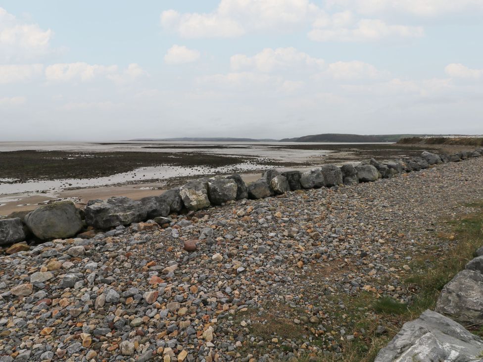A shoreline with rocks and pebbles near water at Chalet 242 Carmarthen Bay Kidwelly