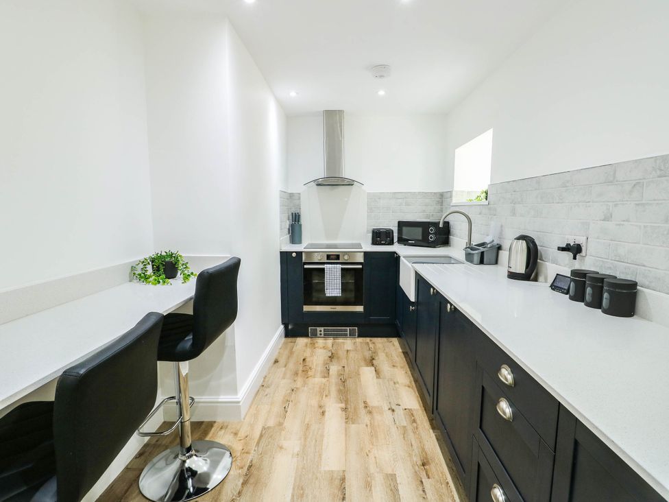 A kitchen with bar stools and appliances at River View in Betws-y-Coed