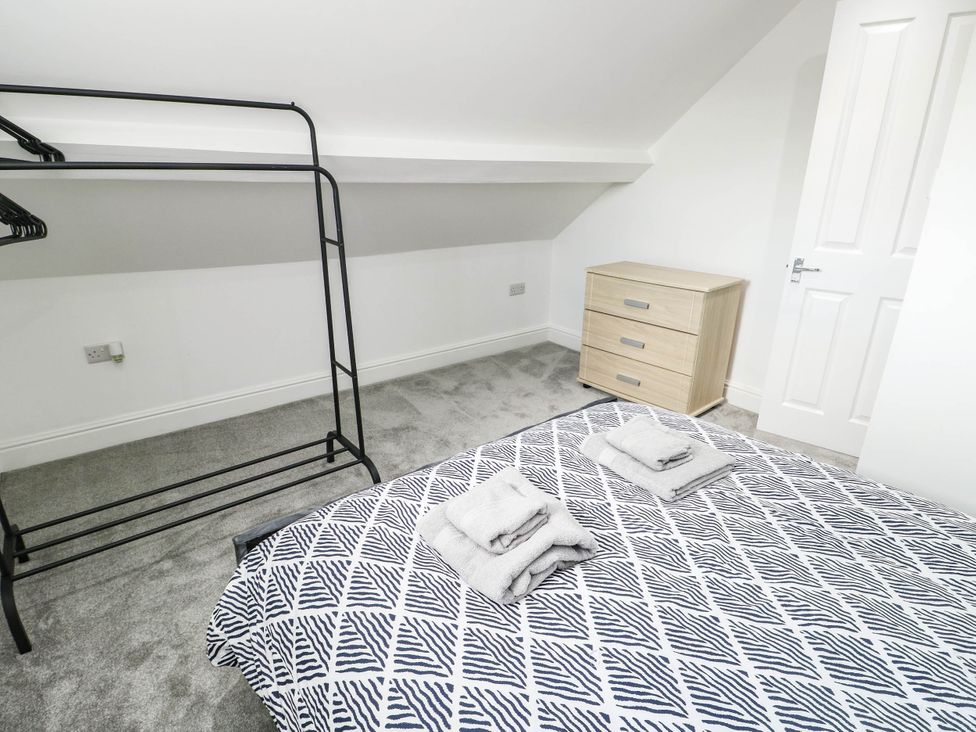 A bedroom with a bed, towels, wardrobe, and a drawer unit at River View in Betws-y-Coed