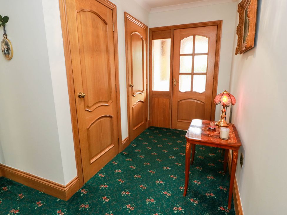 A hallway with doors and a table with a lamp at Wallvilla
