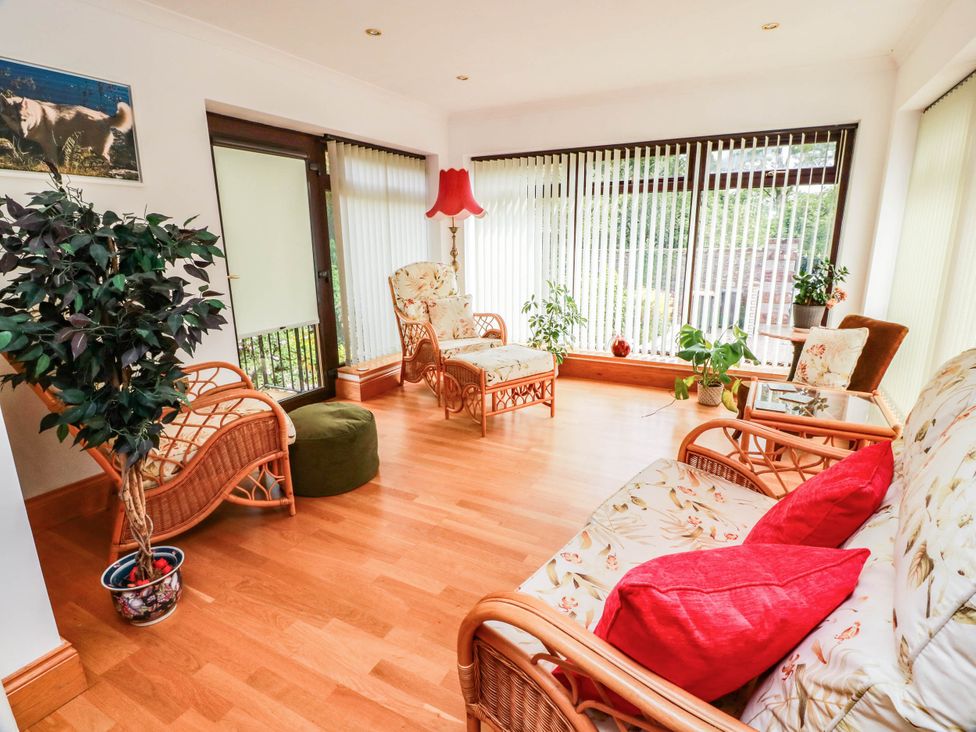 A conservatory with wicker furniture and plants at Wallvilla