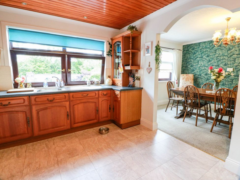A kitchen with wooden cabinets and a dining area at Wallvilla 