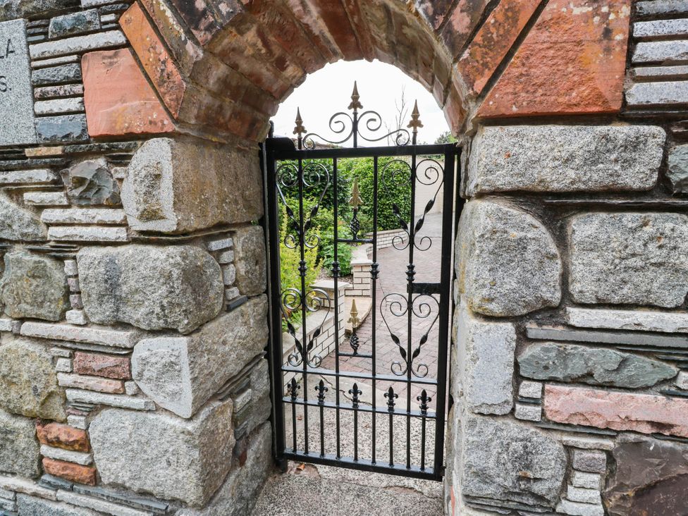 A stone wall with an iron gate leading to a pathway at Wallvilla
