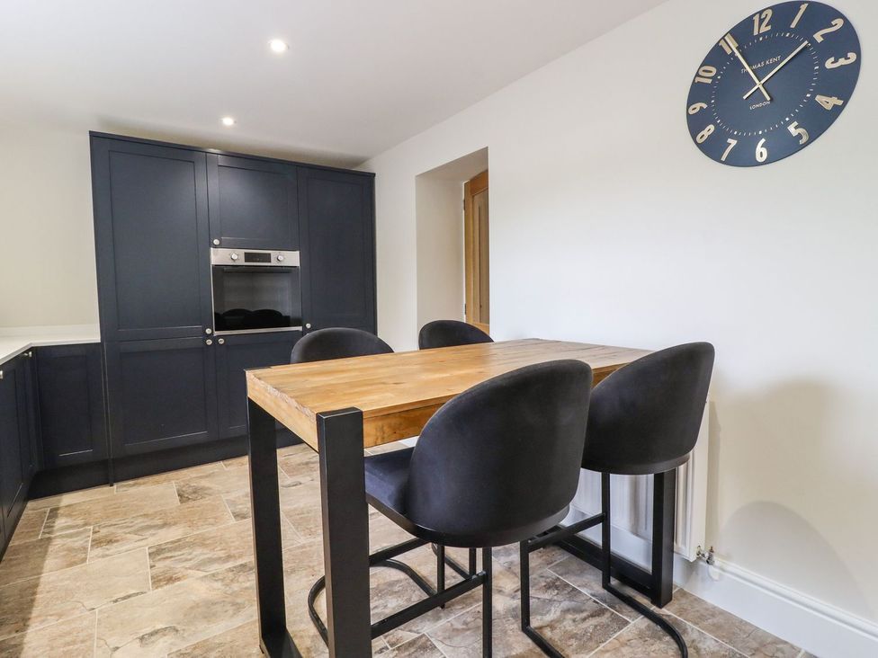 A kitchen with a table and stools at Cottage by the River Burnley