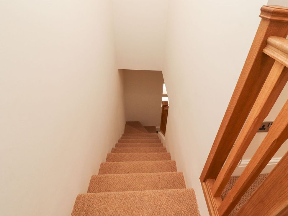 A staircase with carpeted steps and a wooden handrail at Cottage by the River Burnley