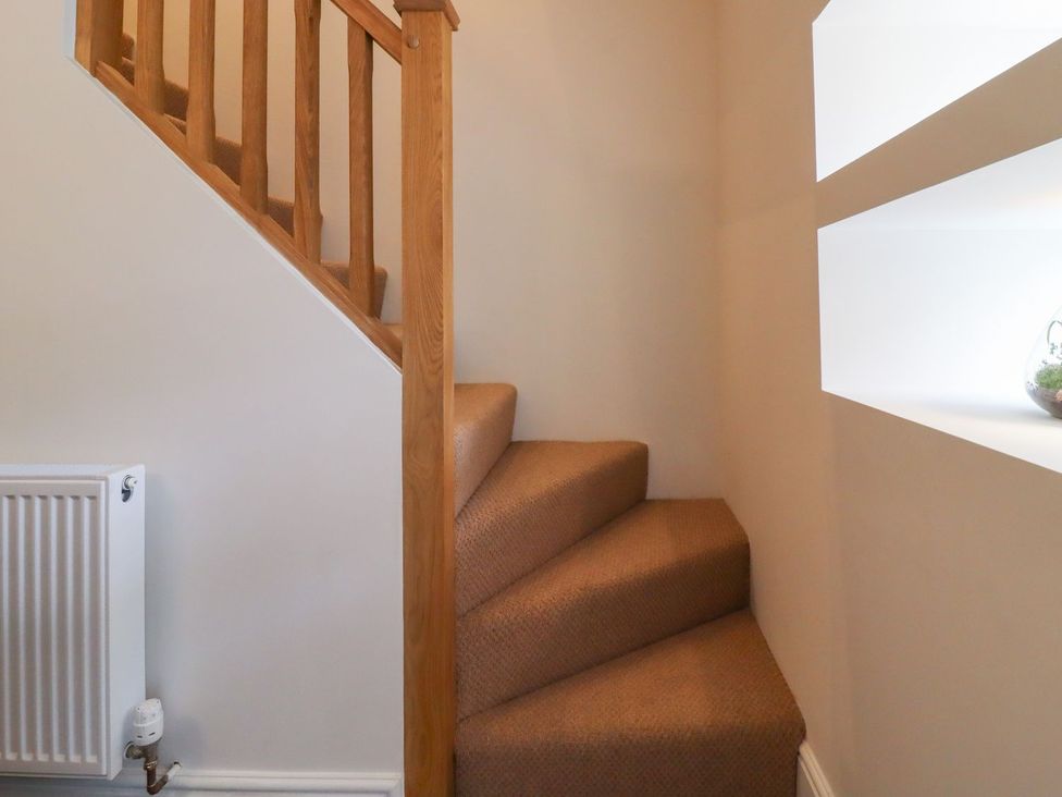 A staircase with carpet and a decorative shelf at Cottage by the River in Burnley