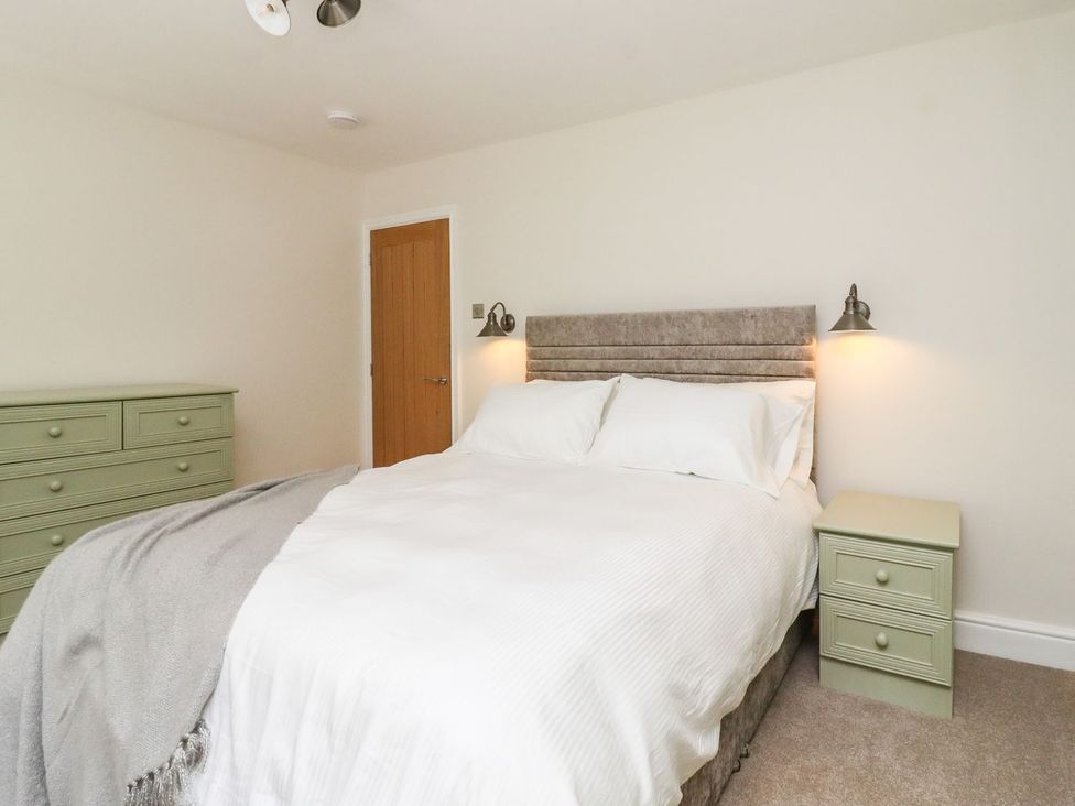 A bedroom with a bed and nightstand at Cottage by the River Burnley