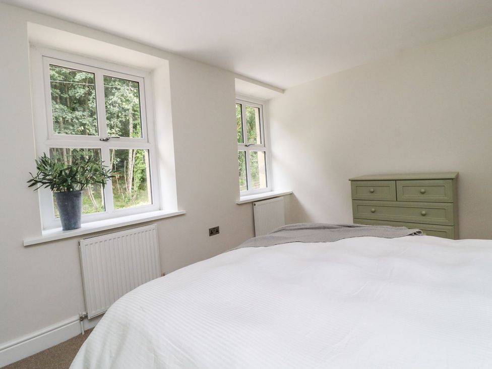 A bedroom with windows and a dresser at Cottage by the River in Burnley