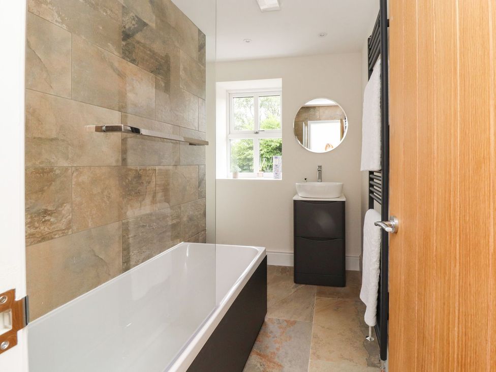 A bathroom with a bathtub and sink at Cottage by the River Burnley