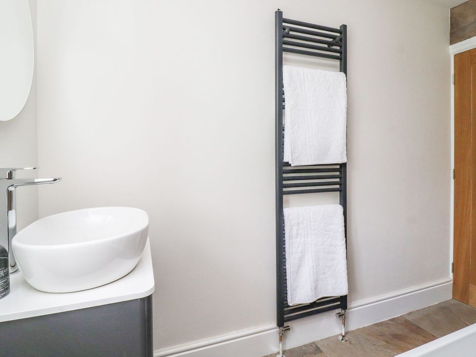 A bathroom with a wash basin and towel rack at Cottage by the River in Burnley