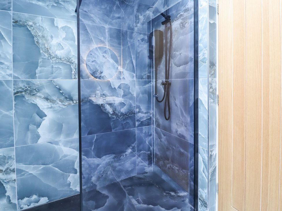 A shower area with blue wall tiles at Cottage by the River in Burnley