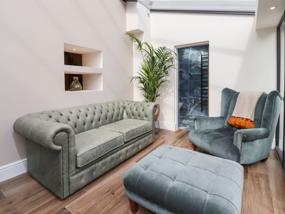 A snug with a sofa and an armchair at Cottage by the River in Burnley