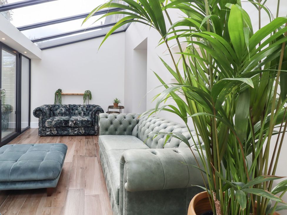 A conservatory with sofas and a potted plant at Cottage by the River in Burnley