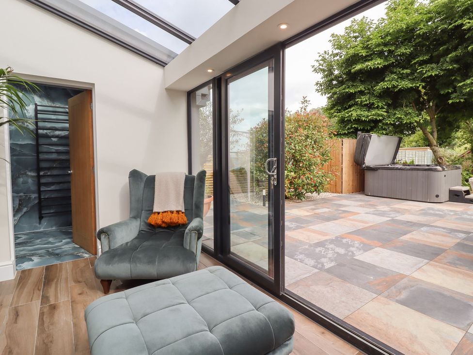 A conservatory with a chair and footstool at Cottage by the River in Burnley