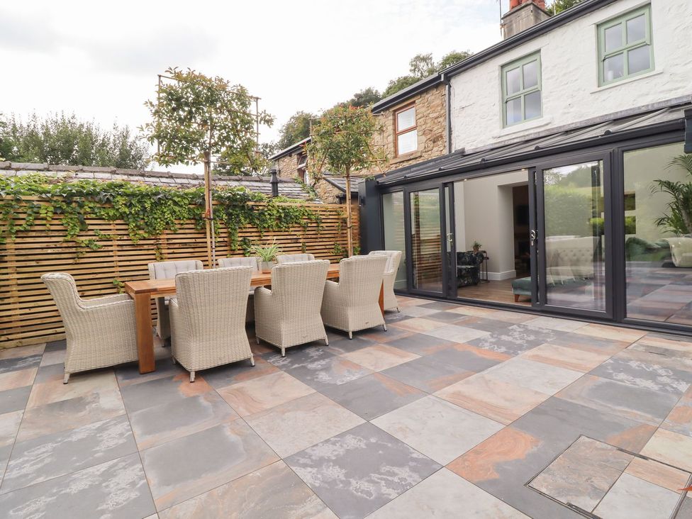 An outdoor patio with a dining table and chairs at Cottage by the River in Burnley
