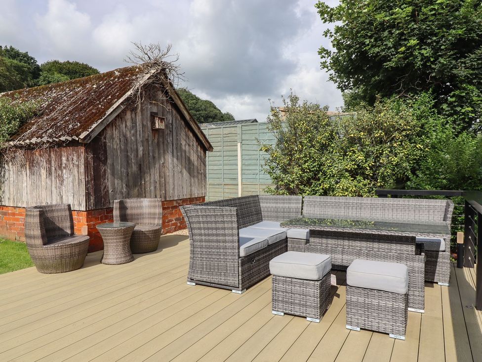 An outdoor patio with wicker furniture and a wooden shed at Cottage by the River in Burnley