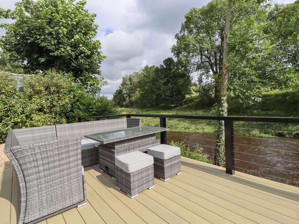 An outdoor seating set on a deck near a river at Cottage by the River Burnley