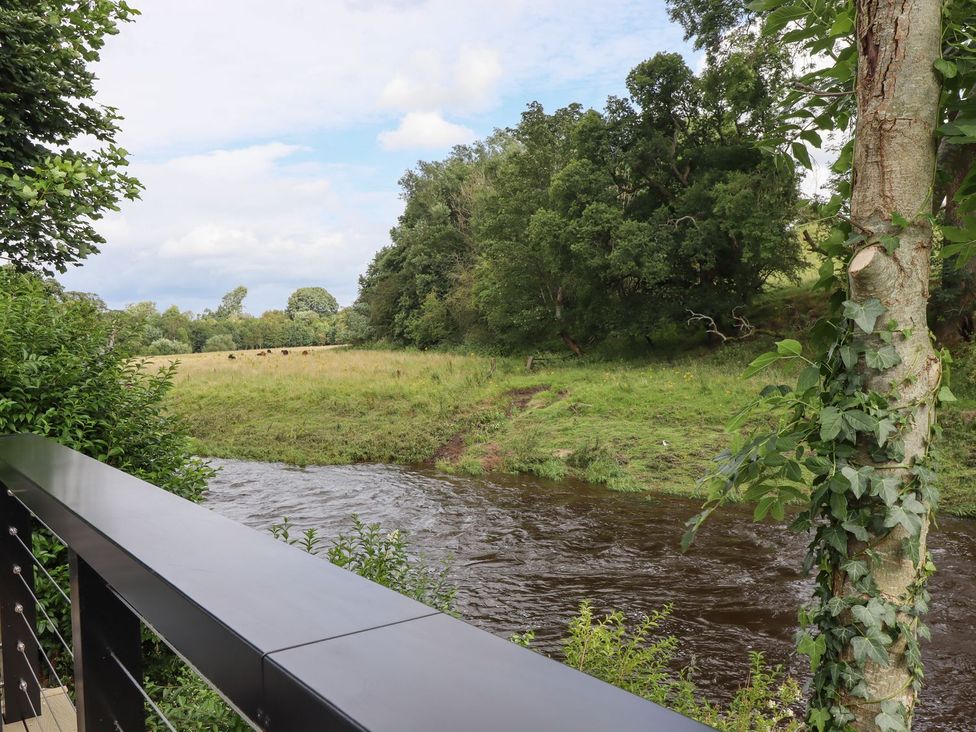 A view of a river with trees and grass at Cottage by the River in Burnley