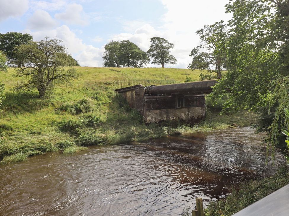 A river with a structure on the bank at Cottage by the River in Burnley